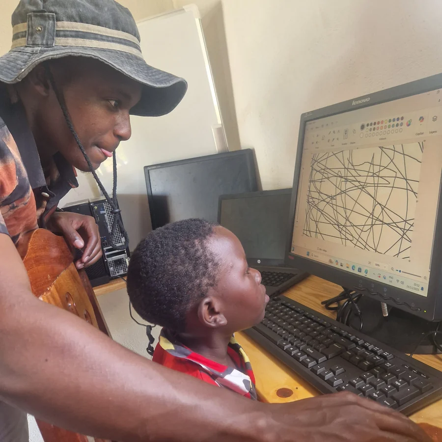 Teacher supporting child at computer